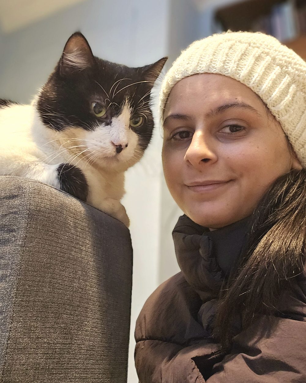 Priya, cat sitter in West London, with a relaxed tuxedo cat at home